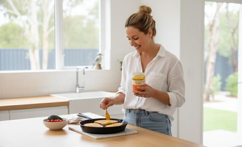 Woman cooking eggs on a stove in a modern kitchen using sacred staples spice ghee